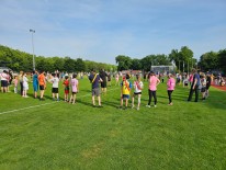 Schülerinnen und Schüler stehen auf einer Wiese und wärmen sich gemeinsam für das Sportfest auf